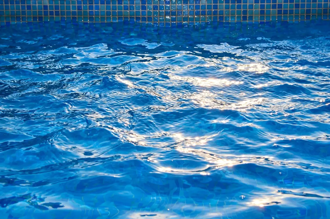 Sunlit pool water with a blue tile edge
